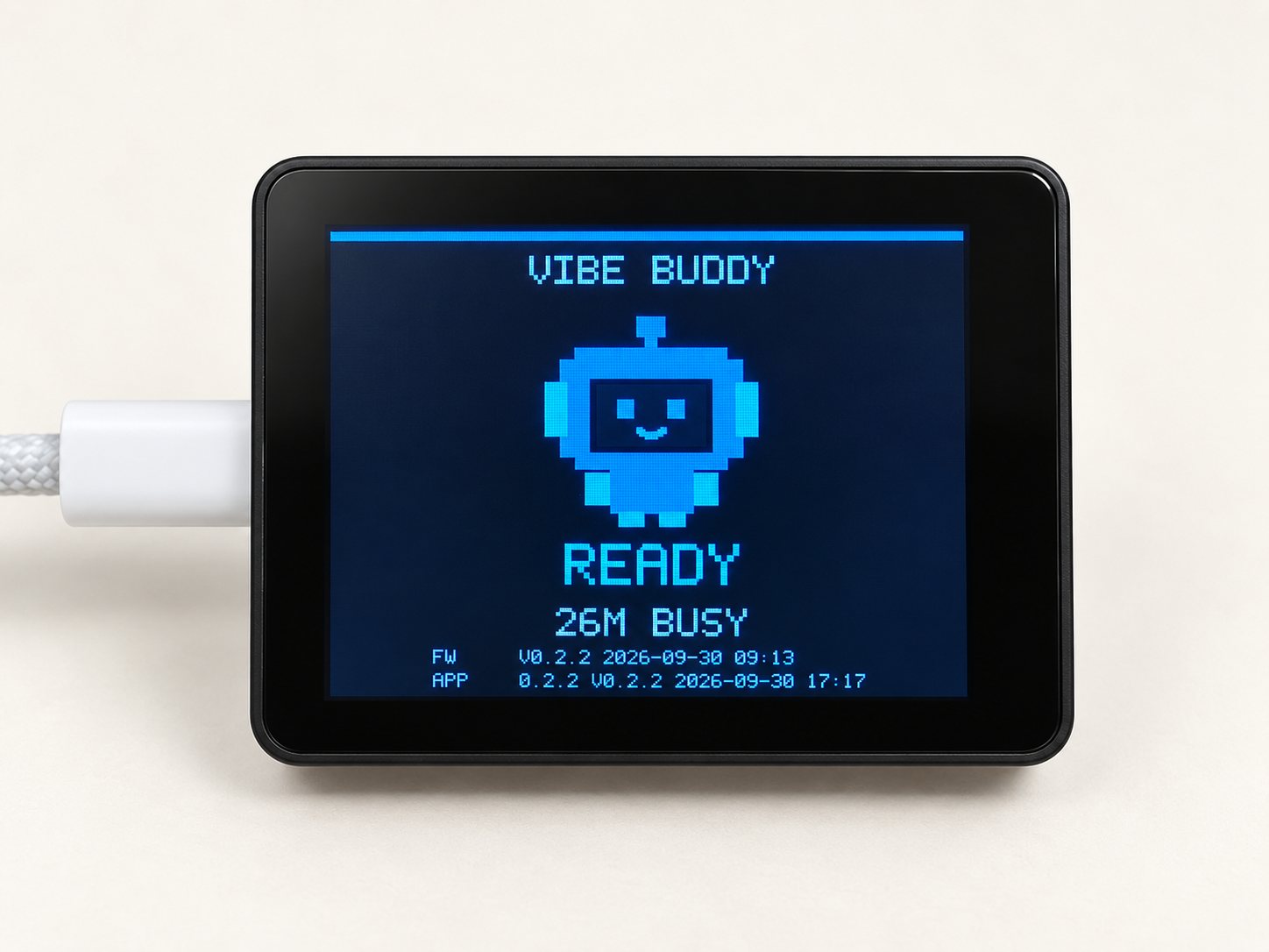 VibeBuddy, a small box with a color screen, connected by a USB-C cable and showing the Ready screen